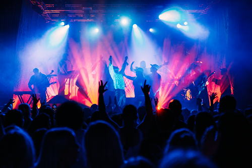 Lyssatt konsertscene med flere musikere på scenen. Foto.