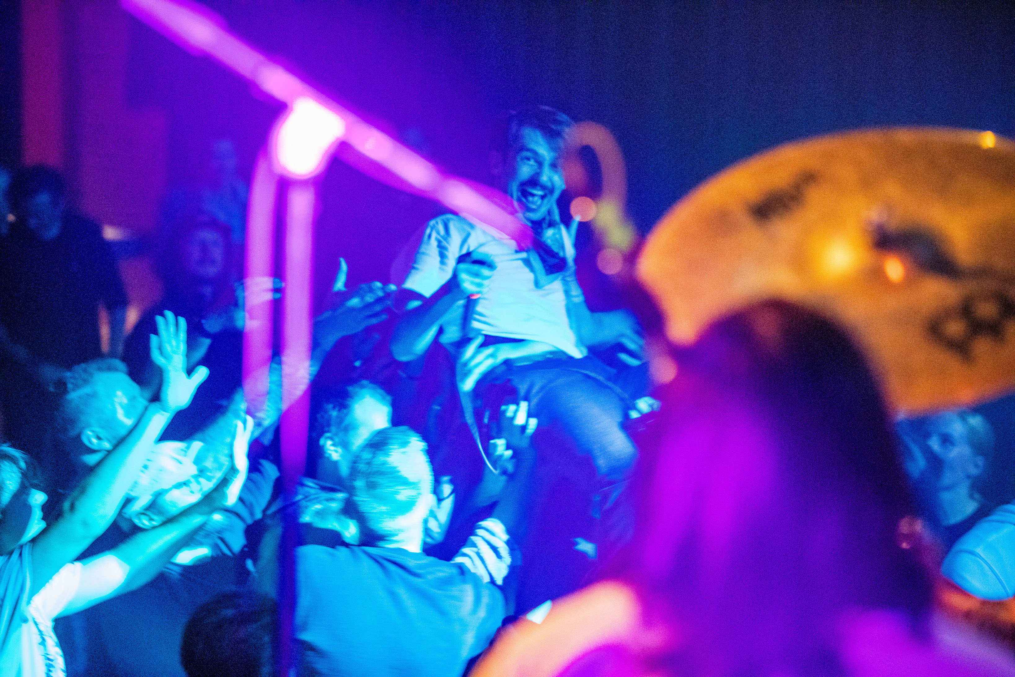 Artist ler og stagediver over publikum med mikrofon i høyre hånd. 