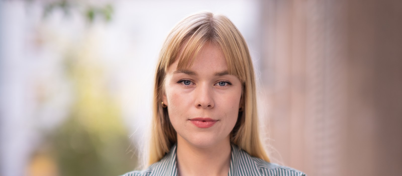 Person i lyse og diffuse omgivelser ser alvorlig inn i kamera. Foto.