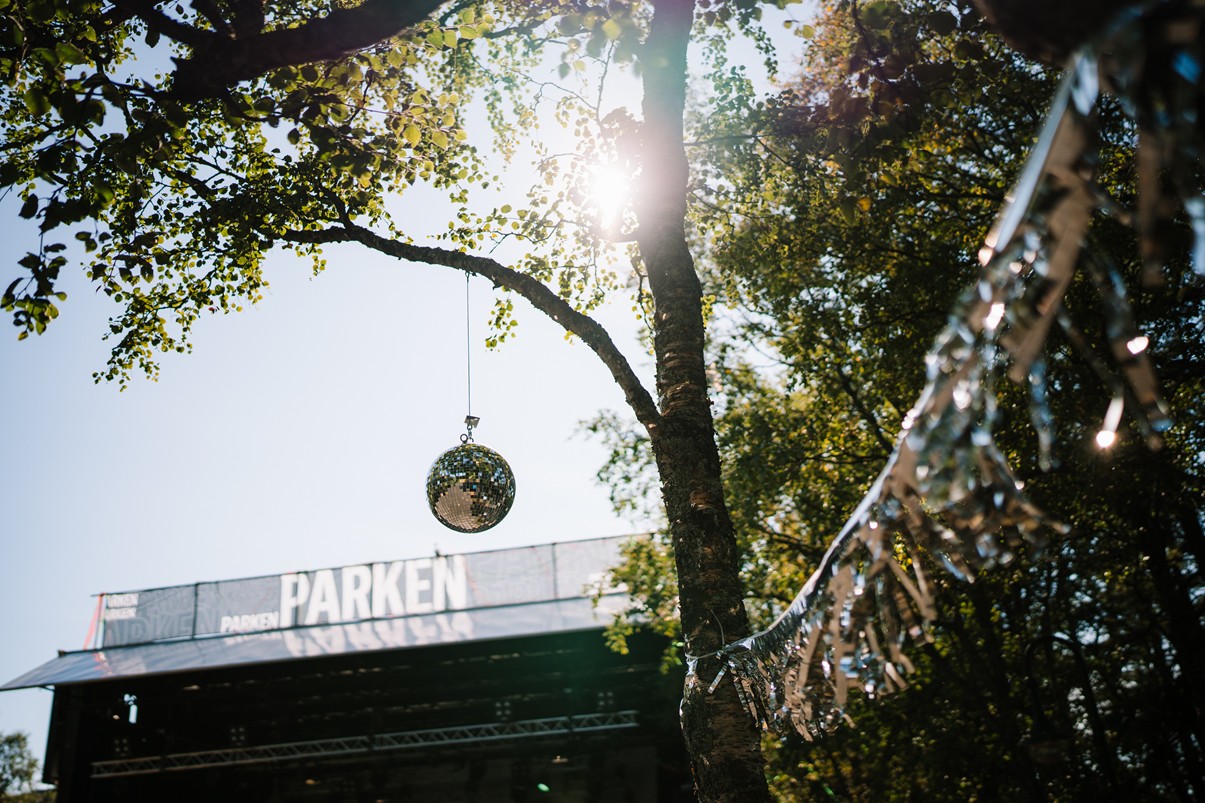En scene på Parkenfestivalen, i solskinn og med diskokule hengende over
