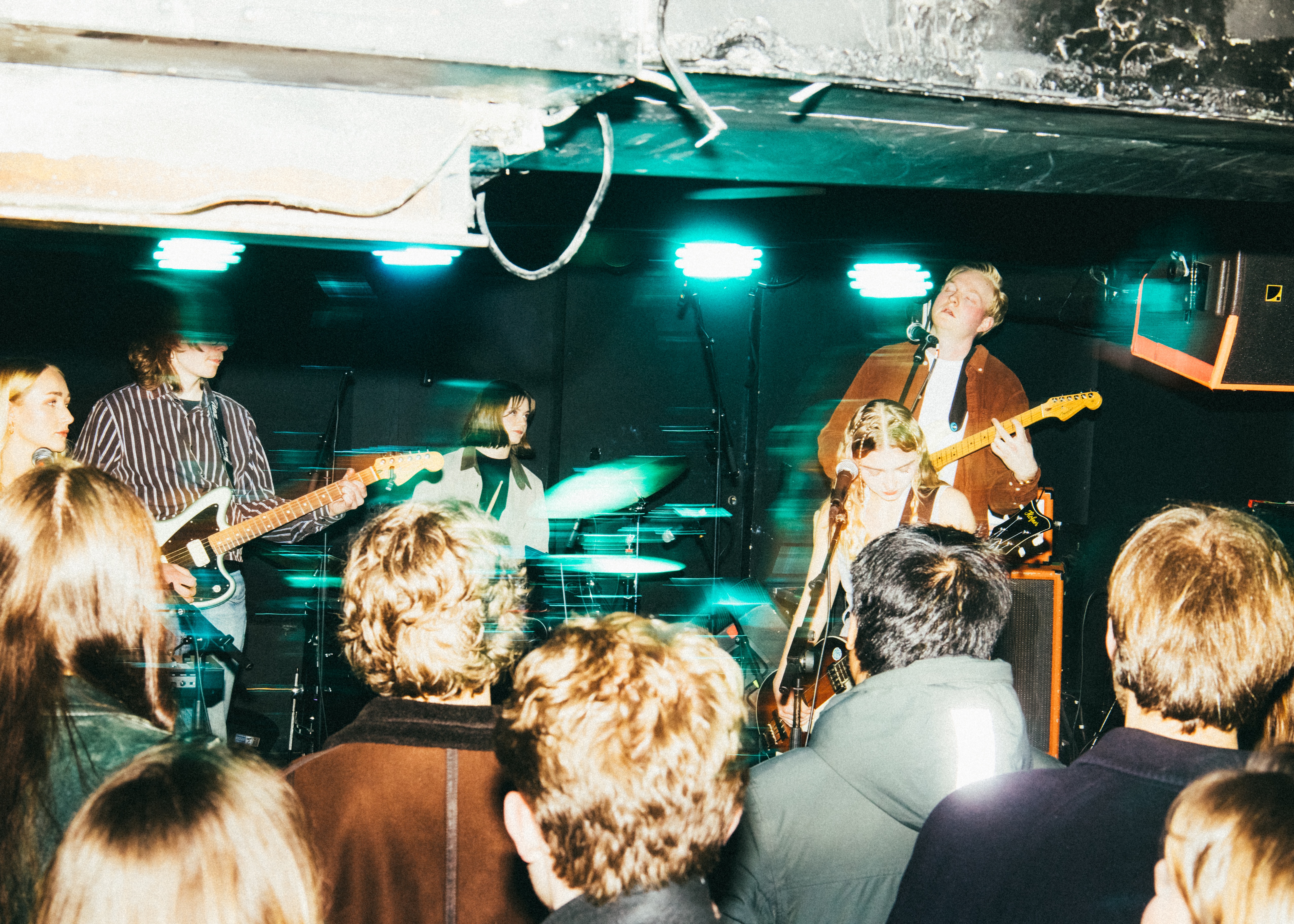 Et ungt band med spiller med innlevelse på en trang klubbscene hvor det er lavt under taket. 
