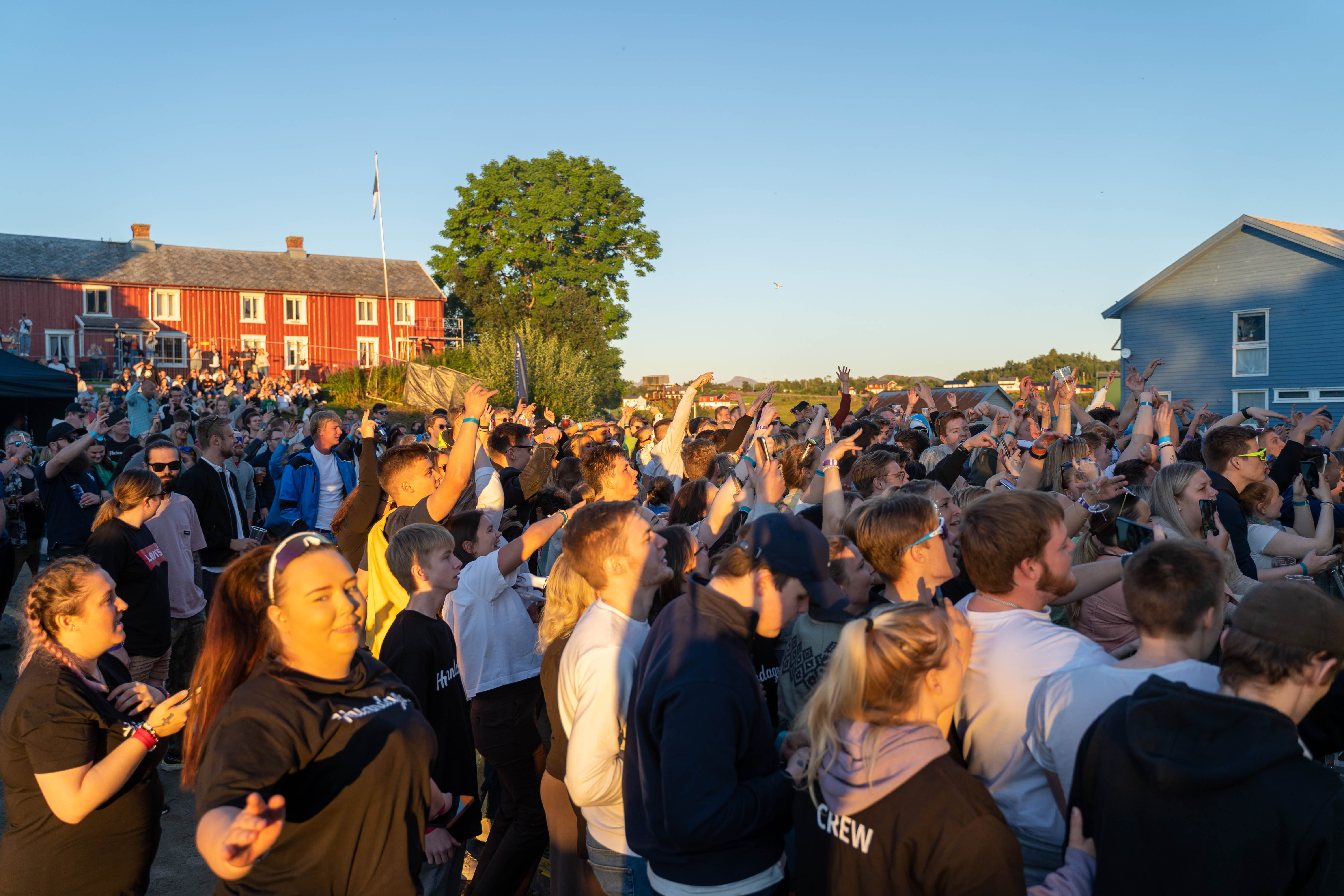 En gruppe mennesker ser mot samme konsert i sollys.